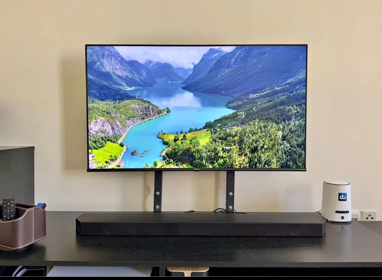 Television displaying a mountain landscape above a black soundbar