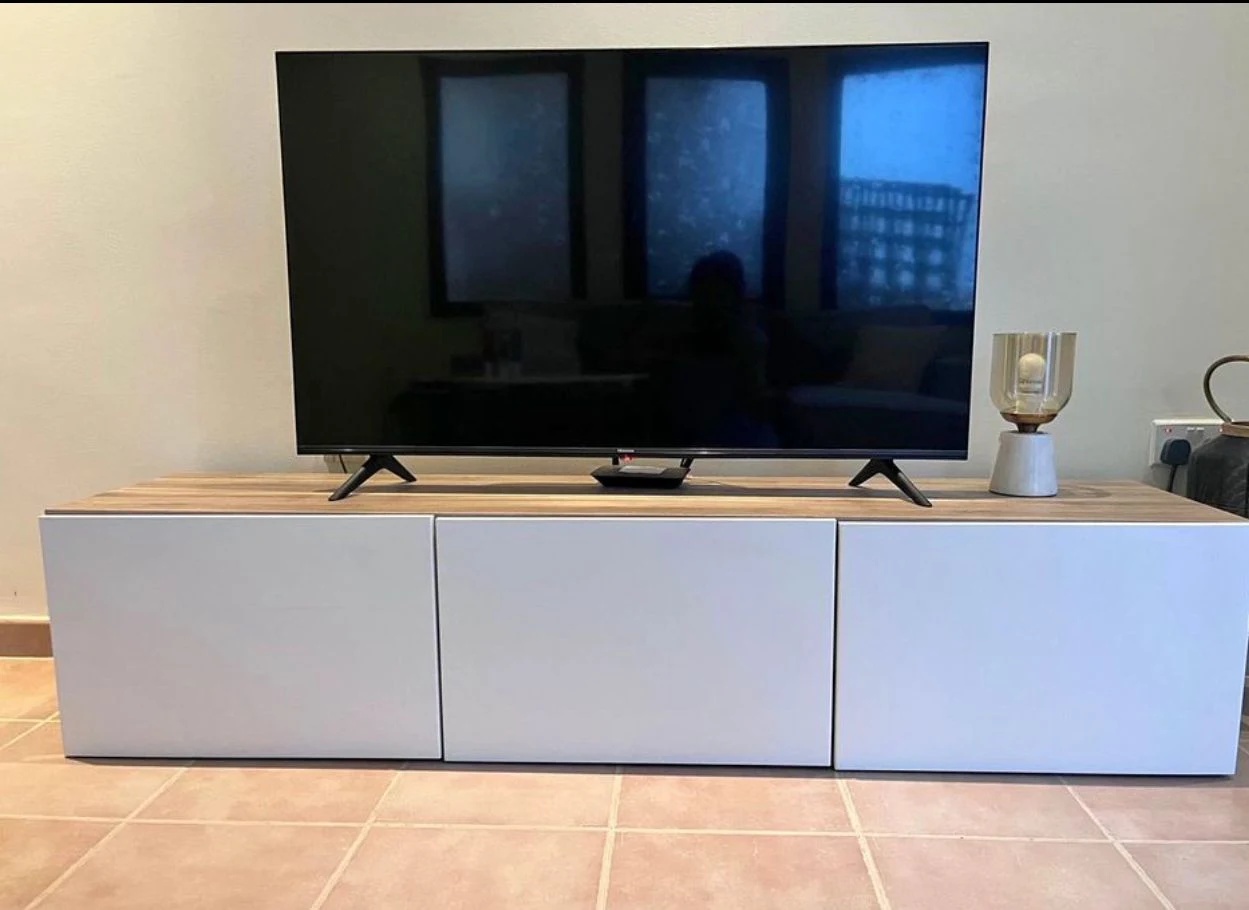 Flat-screen television and remote on a white cabinet